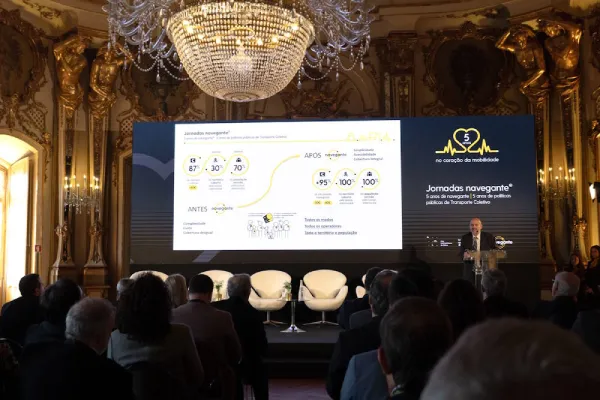 Una sala interna barocca con un maxi-schermo in cui sono proiettati le proiezioni del futuro dei trasporti gratuiti a Lisbona. Un uomo parla dal pulpito ed un gruppo di persone di spalle ascoltano. 