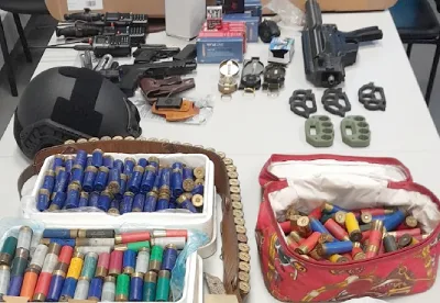 Su un tavolo il materiale sequestrato dalla PJ a seguito dell' allarme estrema destra Portogallo con munizioni, armi, tirapugni un mitra e un caschetto nero.