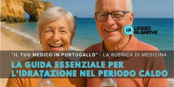 Due persone anziane sorridenti con occhiali da sole con delle bottigliette di acqua in mano a simboleggiare l'importanza di idratarsi nei periodi calid. L'ambientazione è una spiaggia dell'Algarve con il mare e il cielo azzurro di sfondo.