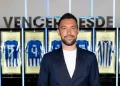 Un primo piano di Francesco Farioli all'interno dello spogliatoio del Porto calcio. L'uomo indossa una giacca blu scura, sullo sfondo si vedono alcune delle maglie del FC Porto.