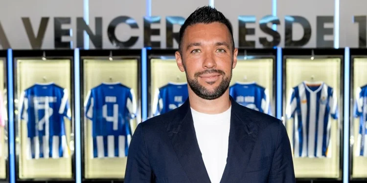 Un primo piano di Francesco Farioli all'interno dello spogliatoio del Porto calcio. L'uomo indossa una giacca blu scura, sullo sfondo si vedono alcune delle maglie del FC Porto.