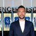 Un primo piano di Francesco Farioli all'interno dello spogliatoio del Porto calcio. L'uomo indossa una giacca blu scura, sullo sfondo si vedono alcune delle maglie del FC Porto.