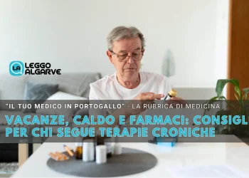 Un uomo anziano con gli occhiali in un salotto, legge i consigli scritti su un flacone, mentre sul tavolo ci sono altri farmaci utili alle terapie croniche.