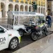 Un auto della polizia effettua dei controlli su tuk-tuk per verificare se irregolari su una strada di Lisbona. Si vede un palazzo con delle colonne sullo sfondo.