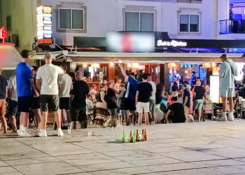 Una piazza di Albufeira con molte persone a chiacchierare e alcune bottiglia di alcolici dopo che il regolamento vieta la vendita.