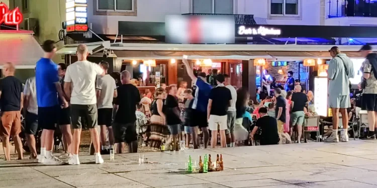 Una piazza di Albufeira con molte persone a chiacchierare e alcune bottiglia di alcolici dopo che il regolamento vieta la vendita.