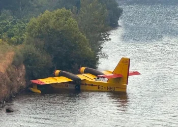 Un aereo Canadair EC-HEU in avaria che galleggia sul fiume Douro in Portogallo, nei pressi della riva con una folta vegetazione di piante.