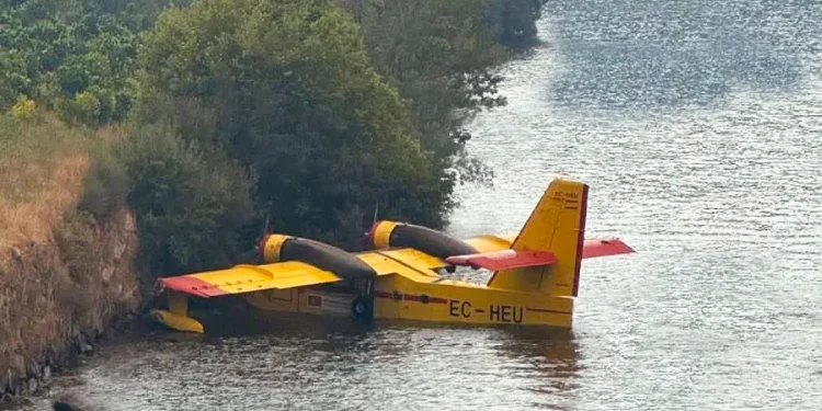 Un aereo Canadair EC-HEU in avaria che galleggia sul fiume Douro in Portogallo, nei pressi della riva con una folta vegetazione di piante.