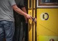 Vicino ad un tram giallo di Lisbona, un borseggiatore sfila un portafoglio nero dalla tasca di un uomo.