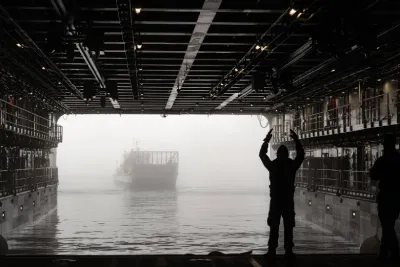 Immagine interna della nave militare italiana Trieste, dove si vede un militare fare segnali ad un mezzo anfibio avvolto dalla nebbia.