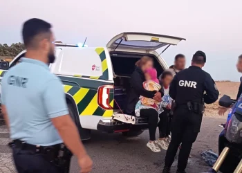 Cinque migranti ricevono i primi soccorsi da parte della GNR dell' Algarve dopo lo sbarco. Sono seduti in un autovettura e si vedono alcuni poliziotti di spalle.