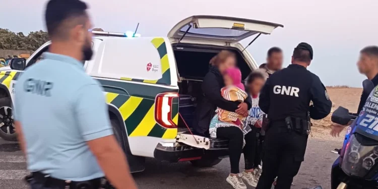 Cinque migranti ricevono i primi soccorsi da parte della GNR dell' Algarve dopo lo sbarco. Sono seduti in un autovettura e si vedono alcuni poliziotti di spalle.