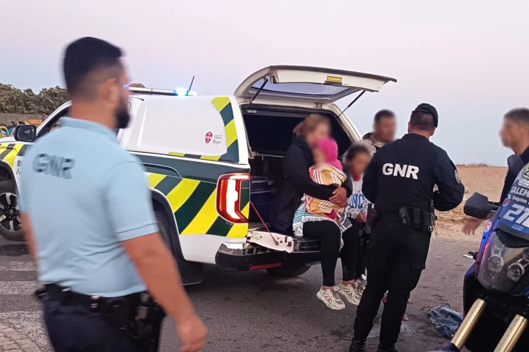 Cinque migranti ricevono i primi soccorsi da parte della GNR dell' Algarve dopo lo sbarco. Sono seduti in un autovettura e si vedono alcuni poliziotti di spalle.