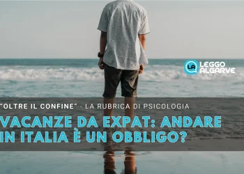 Un uomo di spalle coi piedi immersi nel mare e nulla all'orizzonte a simboleggiare il pensiero dell andare in patria durante le vacanze.