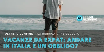Un uomo di spalle coi piedi immersi nel mare e nulla all'orizzonte a simboleggiare il pensiero dell andare in patria durante le vacanze.
