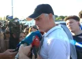 Jose Mourinho con cappellino nero e polo bianca rilascia un intervista come nuovo allenatore del Benfica, ci sono alcuni giornalisti e telecamere attorno a lui mentre parla in alcuni microfoni colorati.