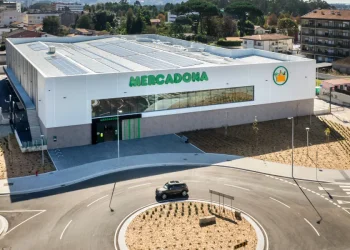Vista aerea di un moderno supermercato Mercadona in Algarve con pannelli solari sul tetto, un ampio ingresso in vetro e un ambiente paesaggistico con un ampio parcheggio.