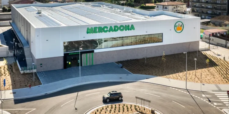 Vista aerea di un moderno supermercato Mercadona in Algarve con pannelli solari sul tetto, un ampio ingresso in vetro e un ambiente paesaggistico con un ampio parcheggio.