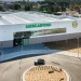 Vista aerea di un moderno supermercato Mercadona in Algarve con pannelli solari sul tetto, un ampio ingresso in vetro e un ambiente paesaggistico con un ampio parcheggio.