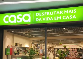 La vetrina con l'insegna verde "casa DESFRUTAR MAIS DA VIDA EM CASA" sovrasta un interno luminoso che espone articoli per la casa e oggetti d'arredamento, poco prima della chiusura del negozio CASA.