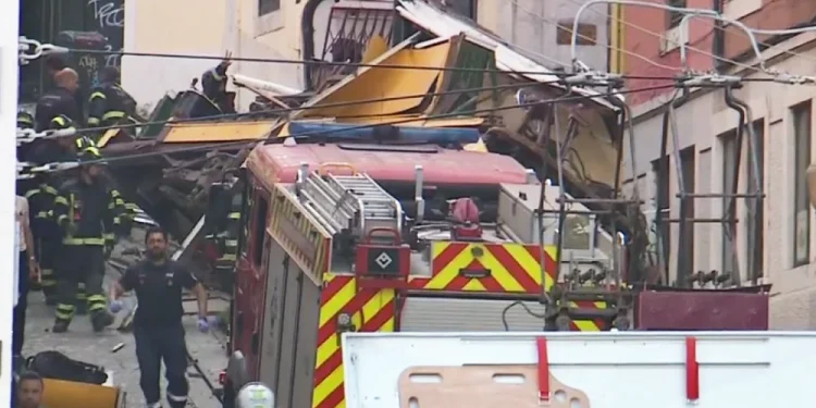 La scena della funicolare di Lisbona deraglia contro il muro di una casa e alcuni soccorritori e pompieri che corrono per dare aggiornamenti.