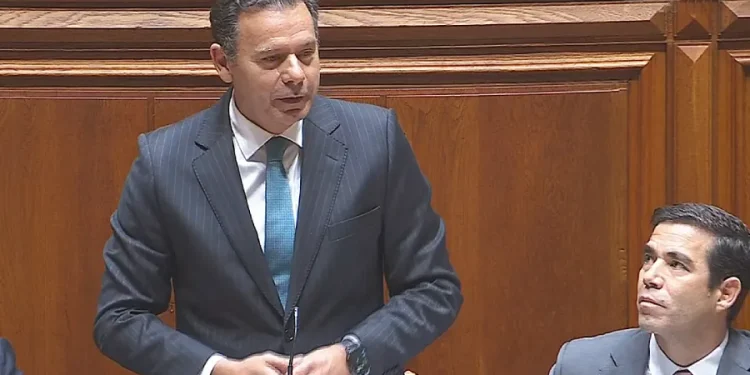In giacca e cravatta, Luis Montengro, il premier del Portogallo discute in parlamento sulla detrazione affitto IRS. Un uomo o guarda con attenzione.