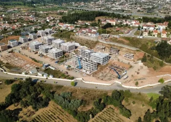 Vista dall'alto di un cantiere edile inserito nel programma portoghese delle case popolari a Coimbra, si vede un terreno piantumato e degli edifici sia in costruzione che terminati.