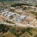 Vista dall'alto di un cantiere edile inserito nel programma portoghese delle case popolari a Coimbra, si vede un terreno piantumato e degli edifici sia in costruzione che terminati.
