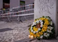 Un bouquet di fiori gialli e bianchi più due candele accese sono poste all'angolo della strada in memoria delle vittime della funicolare di Lisbona, si vedono sullo sfondo le transenne e i fettuccine della polizia.
