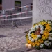 Un bouquet di fiori gialli e bianchi più due candele accese sono poste all'angolo della strada in memoria delle vittime della funicolare di Lisbona, si vedono sullo sfondo le transenne e i fettuccine della polizia.