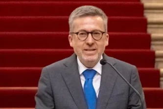 Carlos Moedas sindaco di Lisbona parla sullo sfondo di una scalinata con tappeto rosso difronte ad alcune persone di spalle.