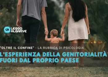 Un bambino piccolo si tiene per mano con due adulti mentre cammina all'aperto, ed il testo italiano in sovrimpressione esplora Diventare genitori all'estero e le sfide uniche della genitorialità al di fuori del proprio Paese per una rubrica di psicologia.