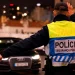 Un agente di polizia che indossa un giubbotto catarifrangente con la scritta "Polícia Segurança Pública" dirige il traffico di notte, facendo segnali con un braccio mentre affronta le auto in avvicinamento, magari fermando qualcuno beccato 15 volte senza patente.