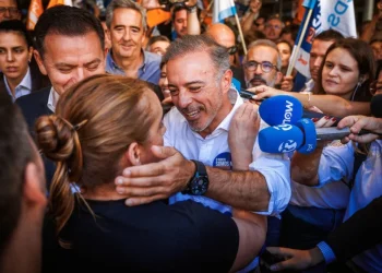 Pedro Duarte sorridente tra la folla stringe la mano e viene abbracciato da un sostenitore dopo la vittoria delle elezioni amministrative di Porto, circondato dalla gente e dai microfoni dei giornalisti in un vivace evento pubblico.