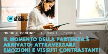 Una donna in piedi accanto a scatoloni, intenta a leggere dei fogli. Un testo in italiano si sovrappone all'immagine, riflettendo sulle sfide emotive affrontate nel momento della partenza e del trasferimento, per una rubrica di psicologia di Leggo Algarve. Finestre luminose illuminano l'ambiente moderno.
