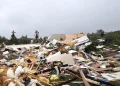 I detriti dei bungalow distrutti sono sparsi sul terreno dopo un tornado in un campeggio di Albufeira in Portogallo, evidenziando il pericolo, tra alberi caduti e cielo nuvoloso sullo sfondo.