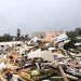 I detriti dei bungalow distrutti sono sparsi sul terreno dopo un tornado in un campeggio di Albufeira in Portogallo, evidenziando il pericolo, tra alberi caduti e cielo nuvoloso sullo sfondo.