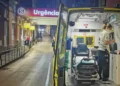 Un'ambulanza con le porte aperte è parcheggiata di notte davanti all'ingresso di un ospedale, dove brilla il cartello Pronto soccorso chiuso. Un paramedico organizza l'attrezzatura all'interno, mentre sullo sfondo sono visibili alcune persone in strada.
