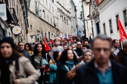 Un numeroso gruppo di persone manifestano a Lisbona per lo sciopero generale in Portogallo, sfilando con bandiere rosse nel mezzo dei palazzi di Lisbona.