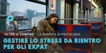 Un'expat stanca con i capelli lunghi, che indossa un cappotto, siede da sola su un vagone della metropolitana di Lisbona, appoggiando la testa al finestrino. Il testo italiano in sovrimpressione parla della gestione della post vacation blues ( lo stress da rientro ) per gli expat.