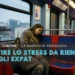 Un'expat stanca con i capelli lunghi, che indossa un cappotto, siede da sola su un vagone della metropolitana di Lisbona, appoggiando la testa al finestrino. Il testo italiano in sovrimpressione parla della gestione della post vacation blues ( lo stress da rientro ) per gli expat.
