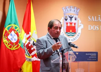 Una foto del ex-sindaco José Carlos Rolo morto a seguito di una complicazione, ha giacca e cravatta, parla ad un microfono difronte alle bandiere di Albufeira.