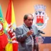 Una foto del ex-sindaco José Carlos Rolo morto a seguito di una complicazione, ha giacca e cravatta, parla ad un microfono difronte alle bandiere di Albufeira.