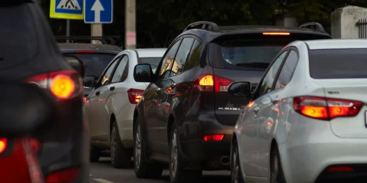 Diverse auto sono allineate in un ingorgo in una strada cittadina, con un attraversamento pedonale e un cartello blu di senso unico visibile sullo sfondo, forse mentre gli automobilisti discutono di pagamento IUC nuove regole che riguardano il pendolarismo urbano.