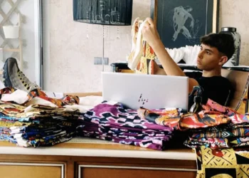 Duarte Silva immagine e osserva le sue borse colorate Capubag, con molti tessuti colorati sulla scrivana ed un pc.