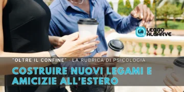 Tre persone in piedi all'aperto con in mano tazze di caffè da asporto, intente a conversare. Un testo in italiano sovrasta l'immagine, promuovendo una rubrica di psicologia su costruire legami all'estero e nuove amicizie.