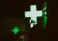 L'insegna verde di una farmacia dove è possibile eseguire un Test HIV a Lisbona. Immagine notturna con una croce verde a led.
