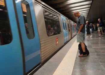 All'interno della stazione della Metro di Lisbona un convoglio è fermo per lavori, mentre un uomo osserva un cellulare in attesa di aggiornamenti.