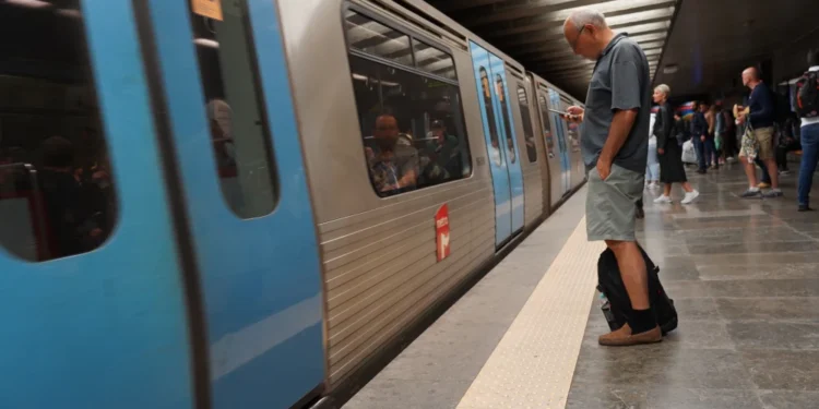 All'interno della stazione della Metro di Lisbona un convoglio è fermo per lavori, mentre un uomo osserva un cellulare in attesa di aggiornamenti.