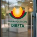 Porta in vetro con il logo e il testo "Segurança Social Direta" in portoghese, caratterizzato da una grafica gialla, rossa e verde. Lo sfondo rivela un interno di ufficio moderno sfocato, che evidenzia la modalità di accesso al sito Seguranca social.